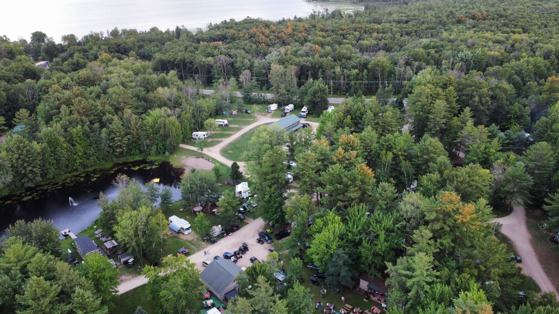 An aerial view of a campground surrounded by trees and a lake.