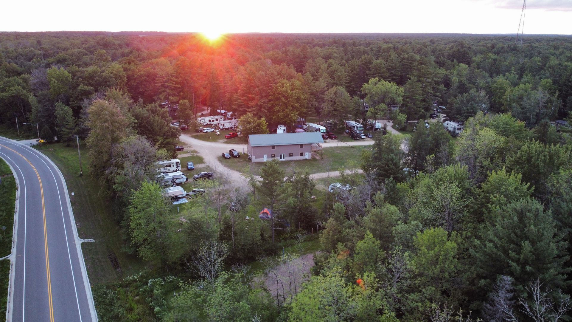 An aerial view of a road surrounded by trees and a house.