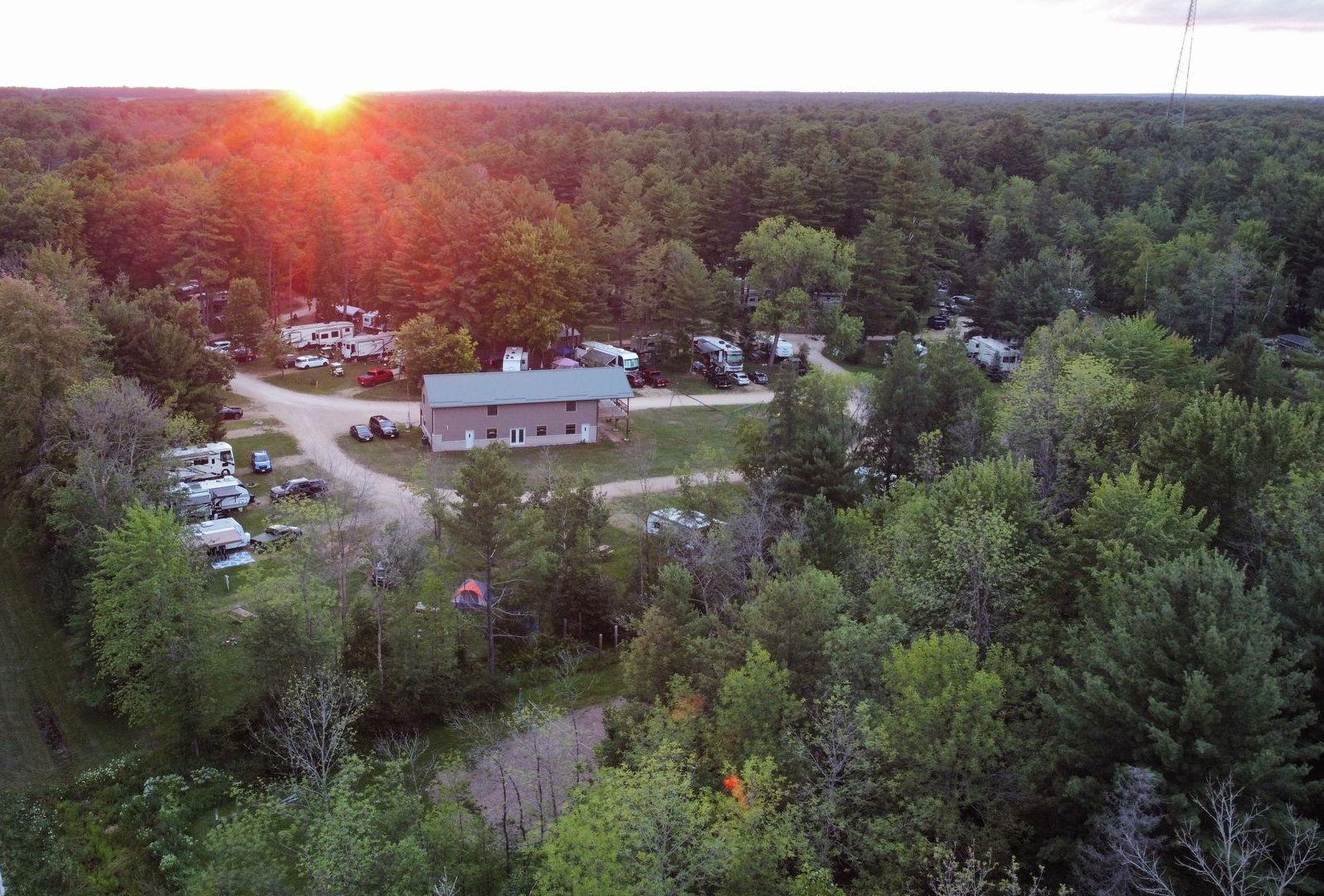 An aerial view of a campground surrounded by trees and a house.