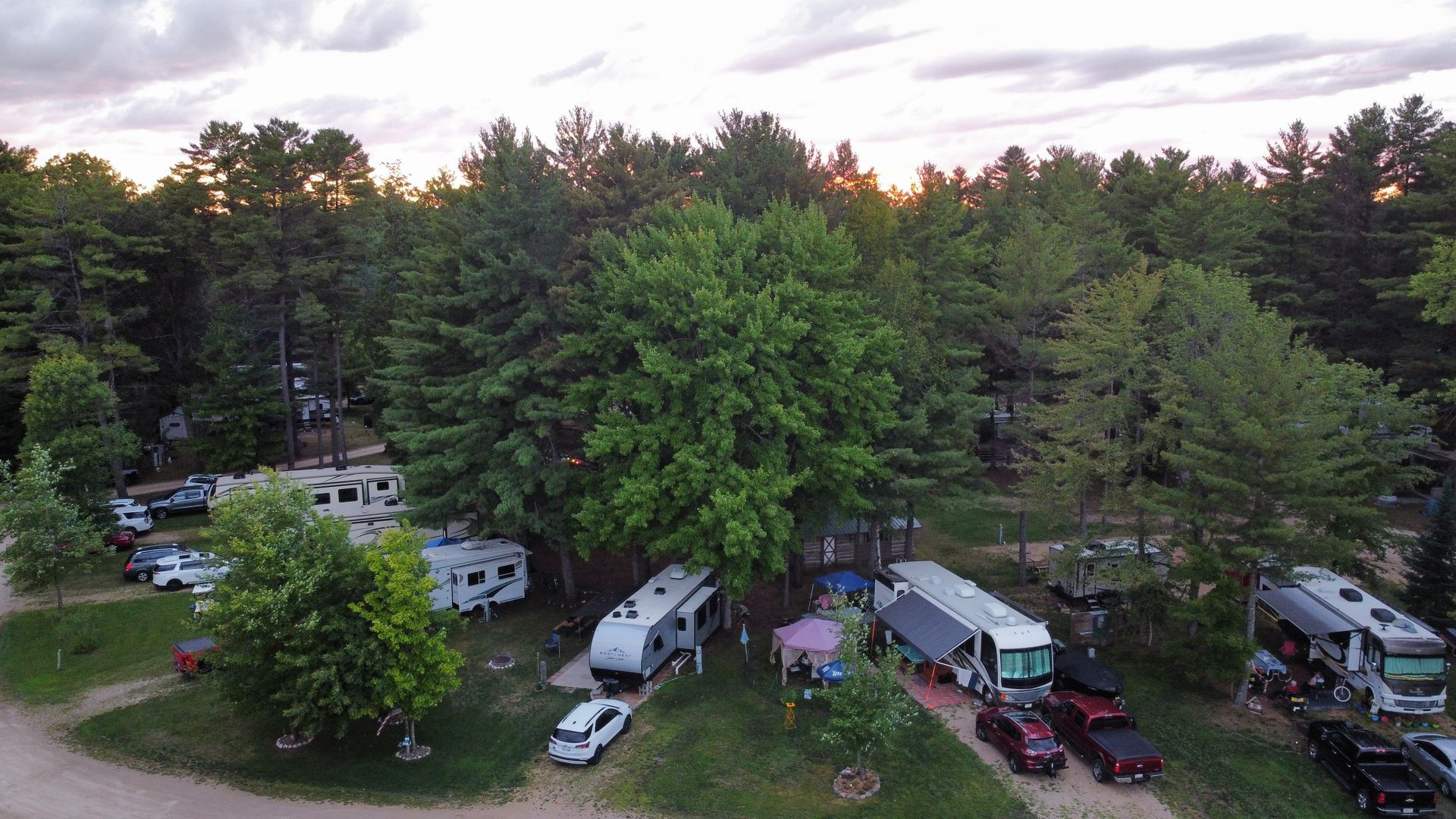 An aerial view of a campground with a lot of rvs parked in the woods.