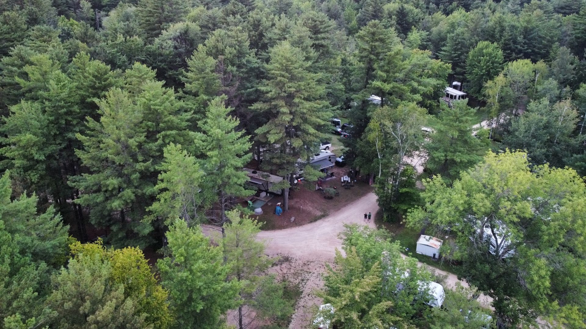 An aerial view of a campground surrounded by trees and a dirt road.