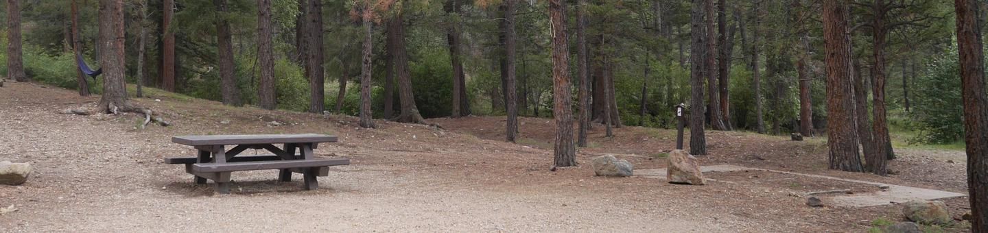 A wooden picnic table in the middle of a forest.