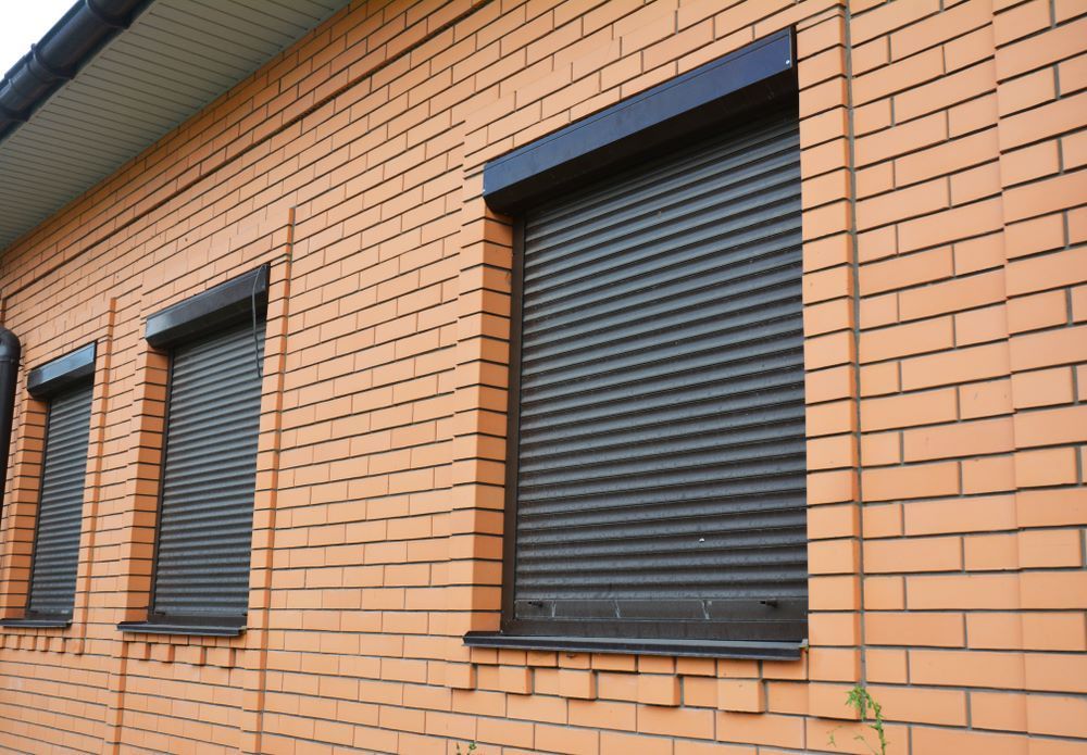 A Brick Building With Black Shutters On The Windows — Maxview Blinds and Shutters in Beresfield, NSW