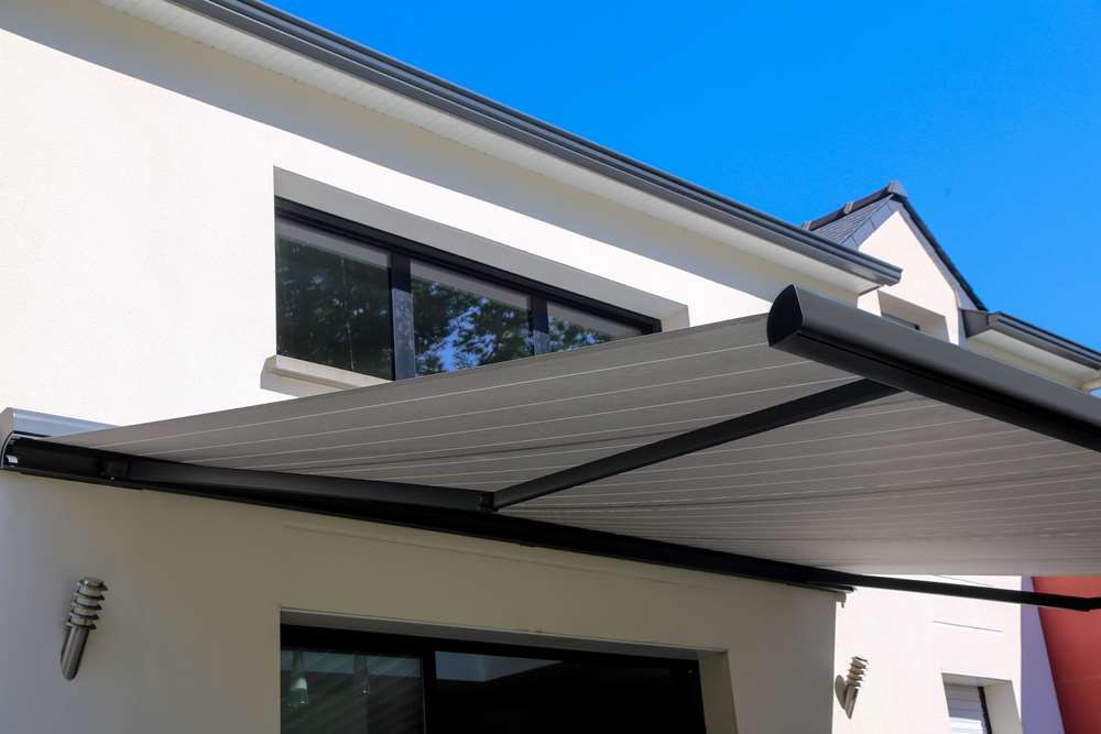 A White House With A Black Awning On The Side Of It — Maxview Blinds and Shutters in Beresfield, NSW