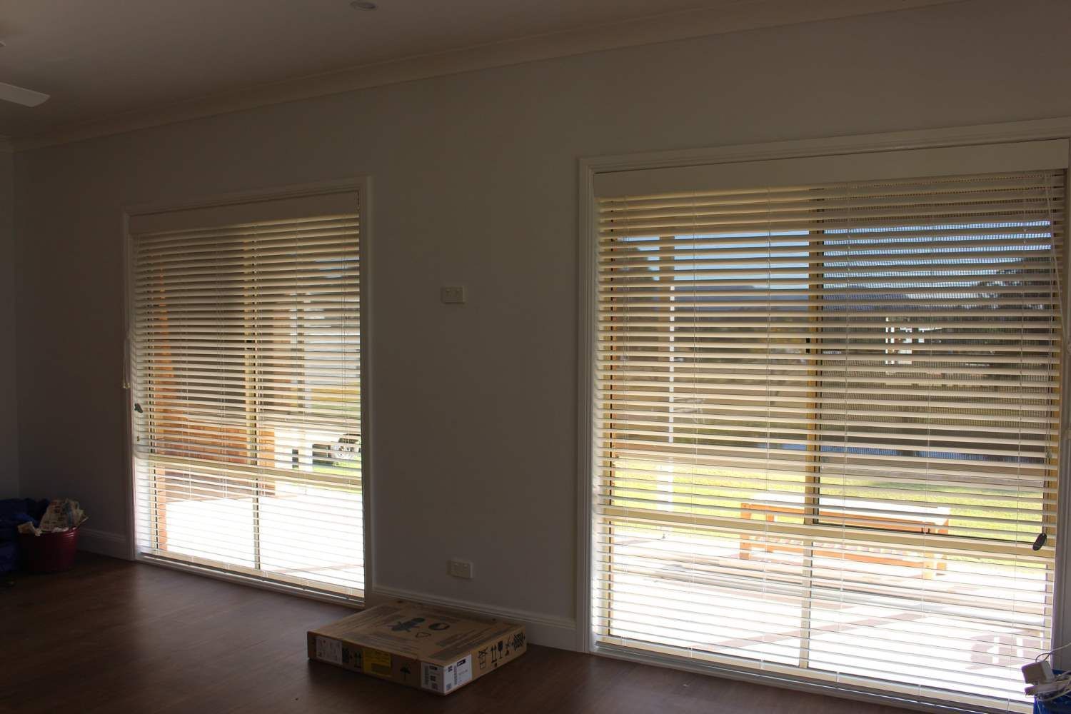 A Living Room With Blinds On The Windows And A Box On The Floor — Maxview Blinds and Shutters in Beresfield, NSW