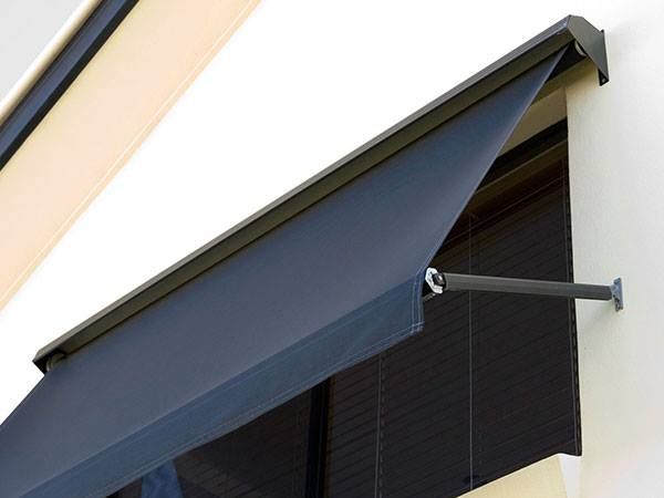 A Blue Awning Is Hanging From The Side Of A Building — Maxview Blinds and Shutters in Beresfield, NSW