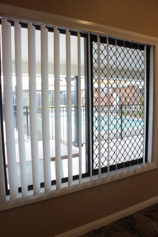 A Room With A Large Window With Vertical Blinds And A View Of A Pool — Maxview Blinds and Shutters in Beresfield, NSW