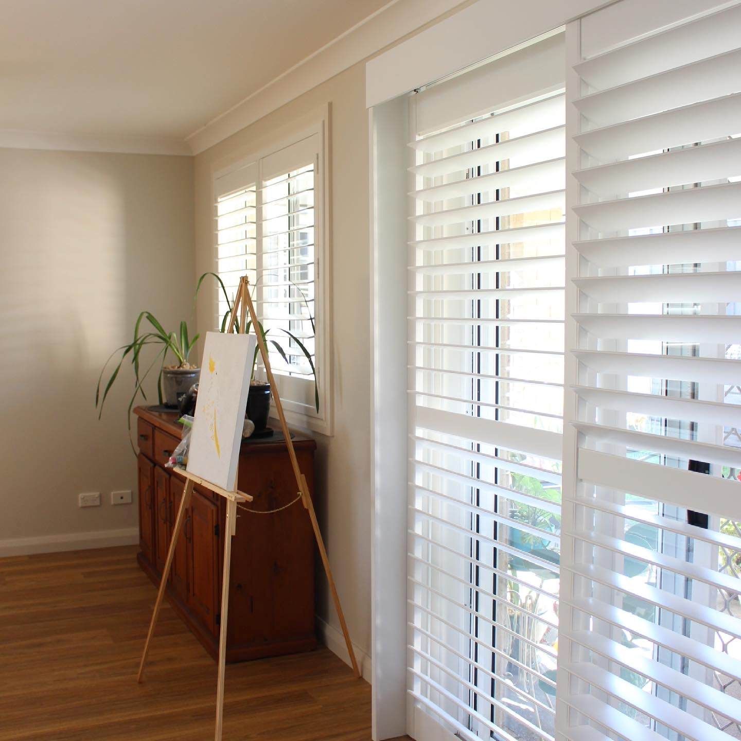 A Room With A Painting Easel And Shutters On The Windows — Maxview Blinds and Shutters in Beresfield, NSW