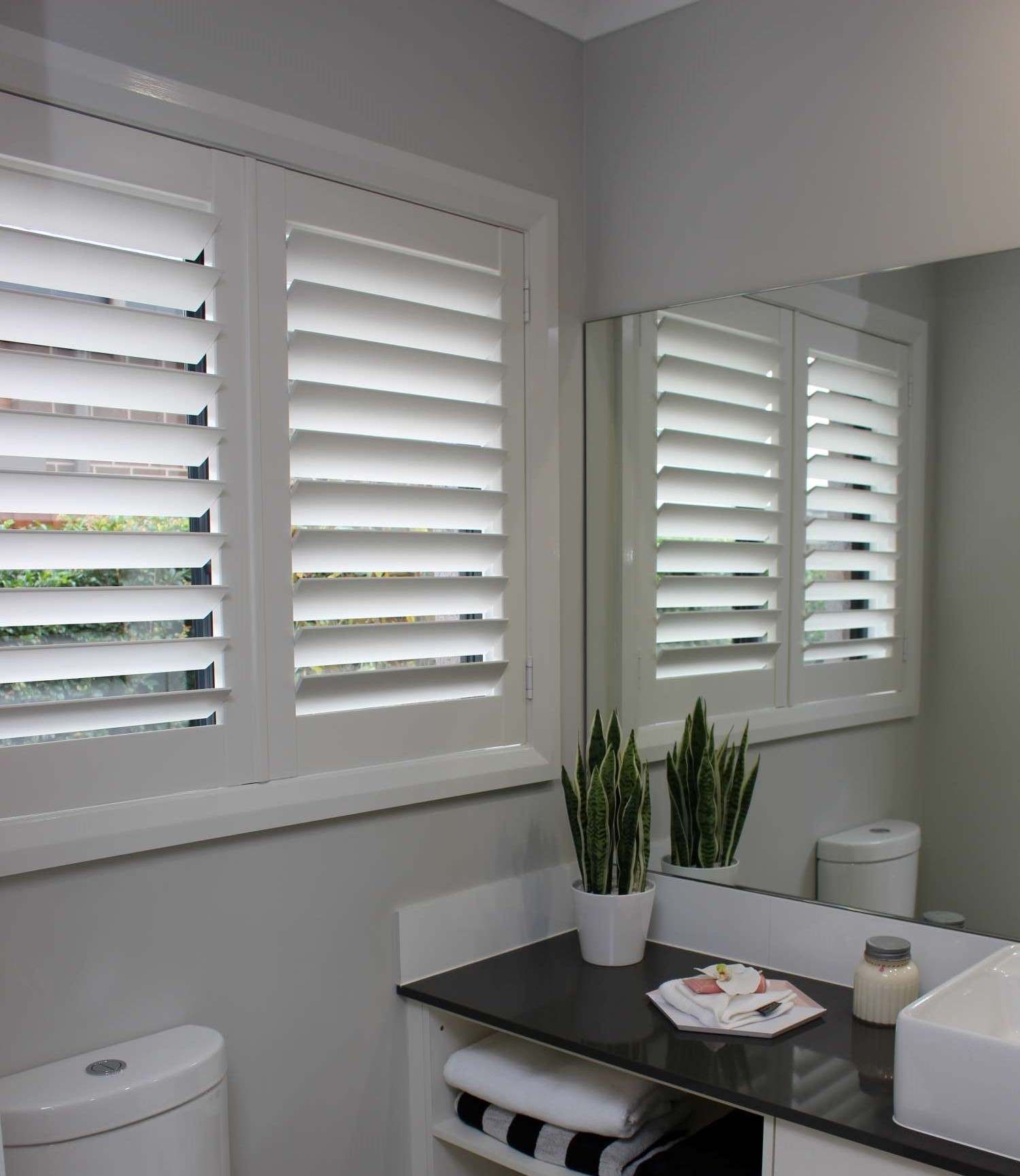 A Bathroom With Shutters On All Four Windows And A Sink — Maxview Blinds and Shutters in Beresfield, NSW