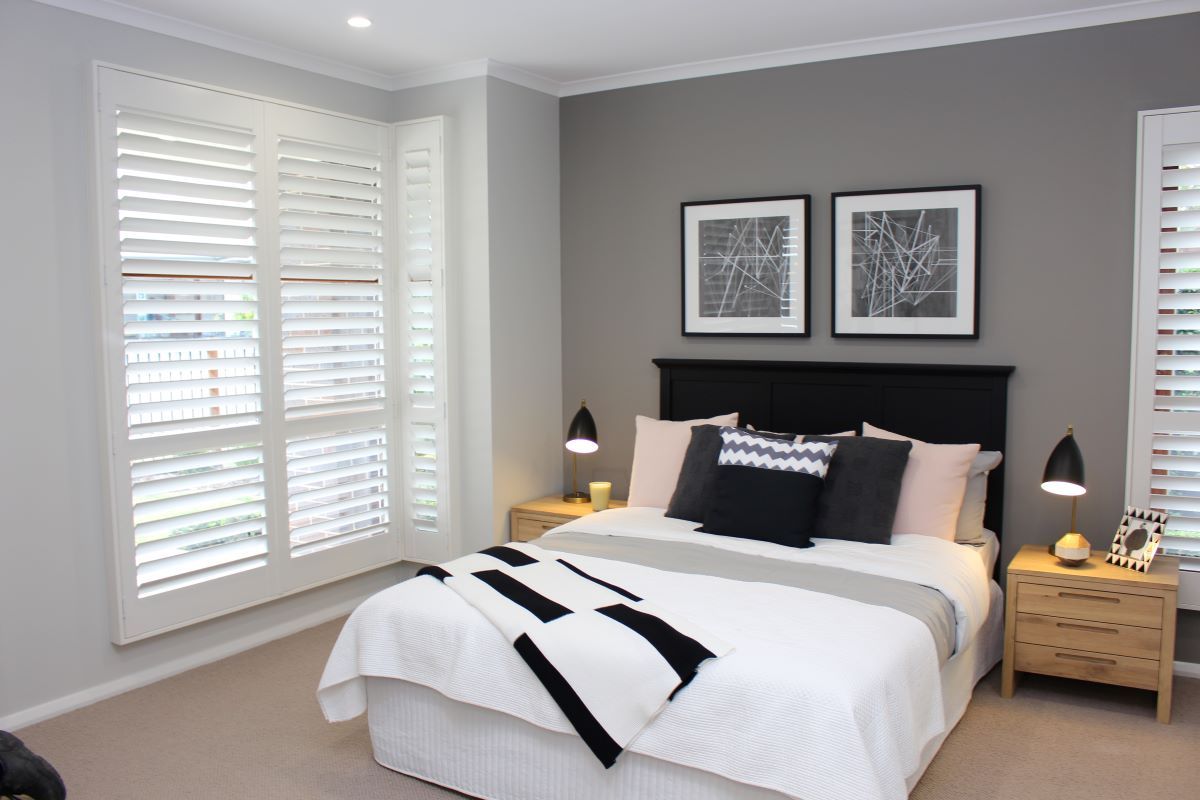 A Bedroom With A Bed, Nightstands, And Shutters On The Windows — Maxview Blinds and Shutters in Beresfield, NSW