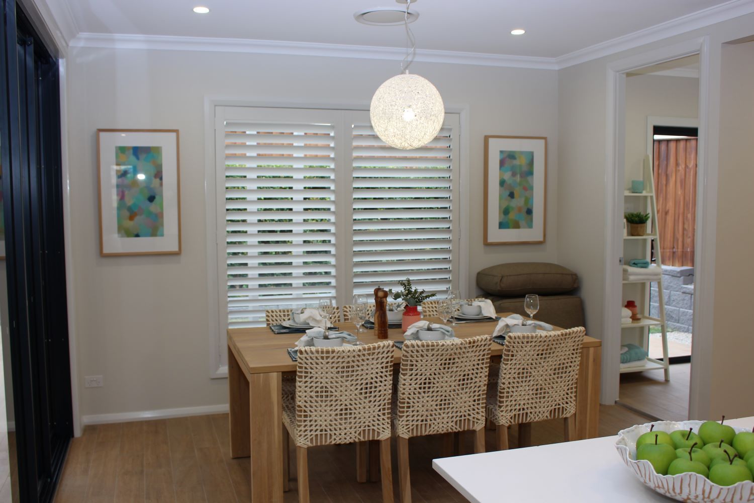 A Dining Room With A Table And Chairs And Window Shutter — Maxview Blinds and Shutters in Beresfield, NSW