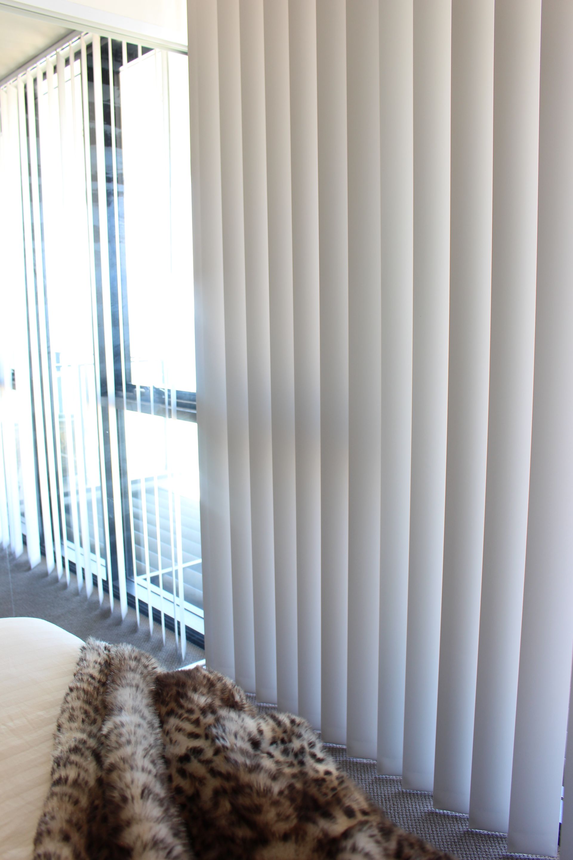A Living Room With Vertical Blinds On A Sliding Glass Door — Maxview Blinds and Shutters in Beresfield, NSW
