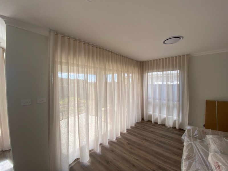 A Bedroom Featuring A Sliding Glass Door With White Curtains — Maxview Blinds and Shutters in Beresfield, NSW