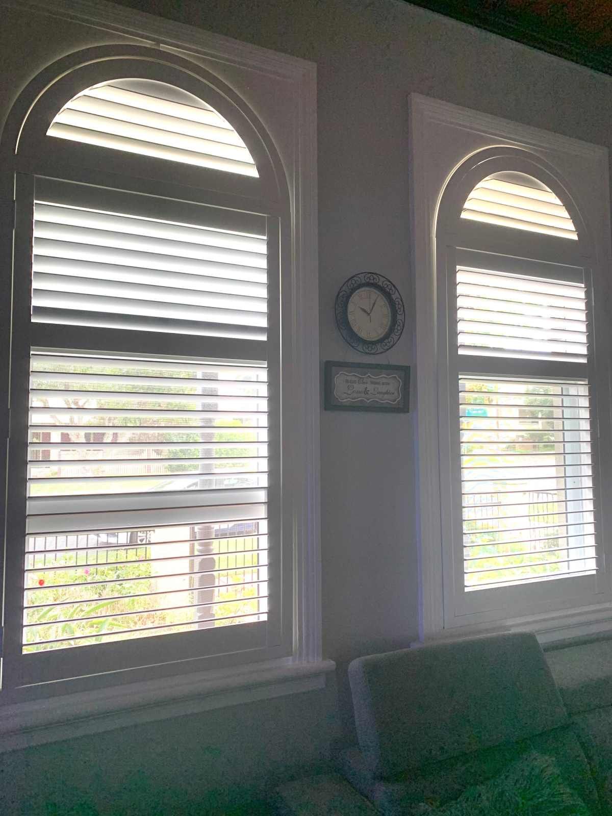 A Living Room With Two Arched Windows With Shutters — Maxview Blinds and Shutters in Beresfield, NSW