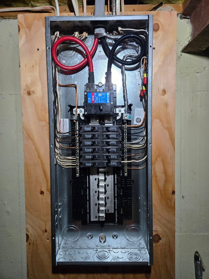 Open electrical panel with wires and circuit breakers mounted on a wooden backboard.