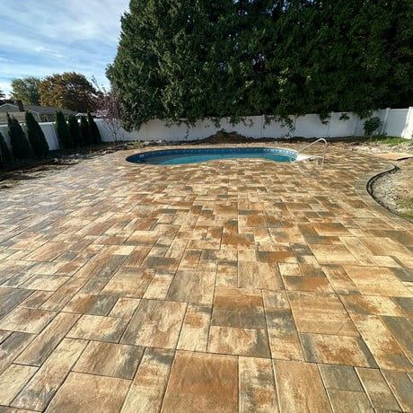 A brick patio with a pool in the backyard.