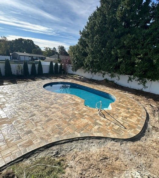 A large swimming pool is surrounded by a brick patio