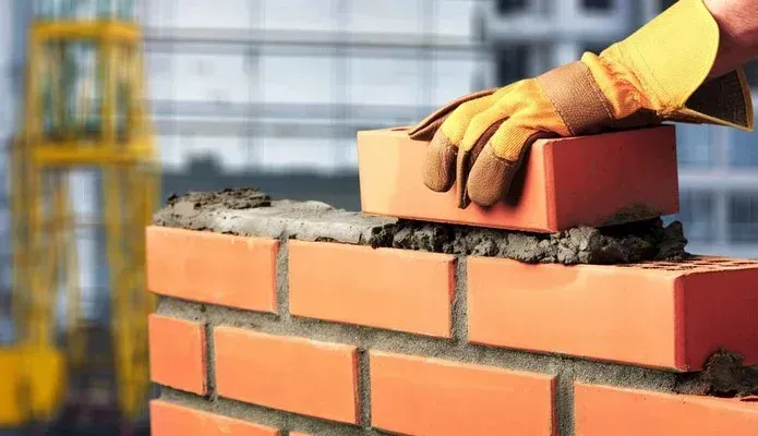 A person is laying bricks on top of a brick wall.