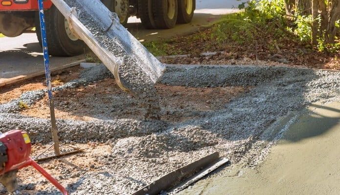 A concrete truck is pouring concrete into a driveway.