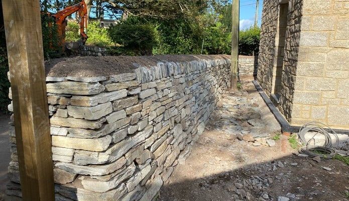 A stone wall is being built in front of a brick building.