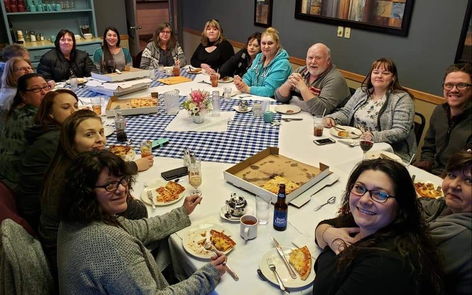 A group of people are sitting around a table eating pizza.