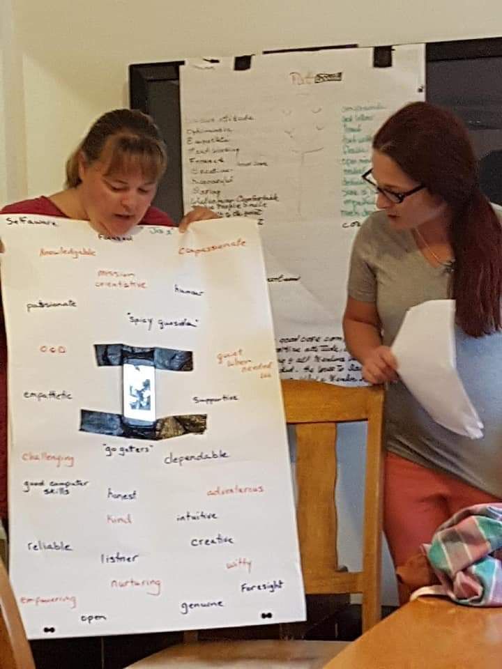 Two women are holding up a poster with a picture of a cell phone on it