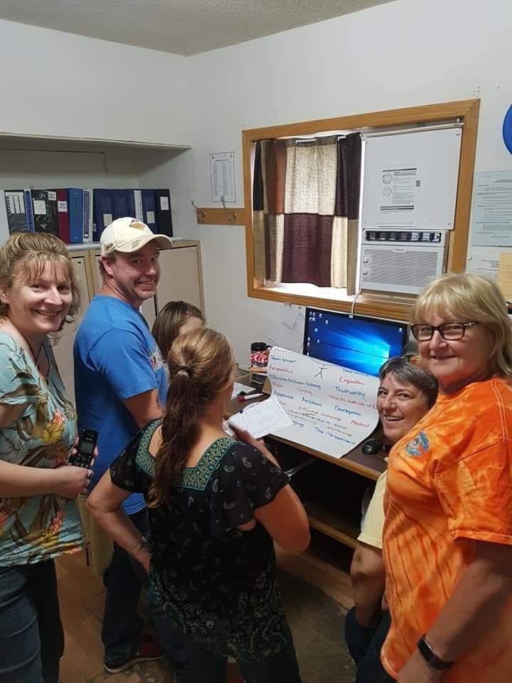 A group of people are standing around a computer in a room.
