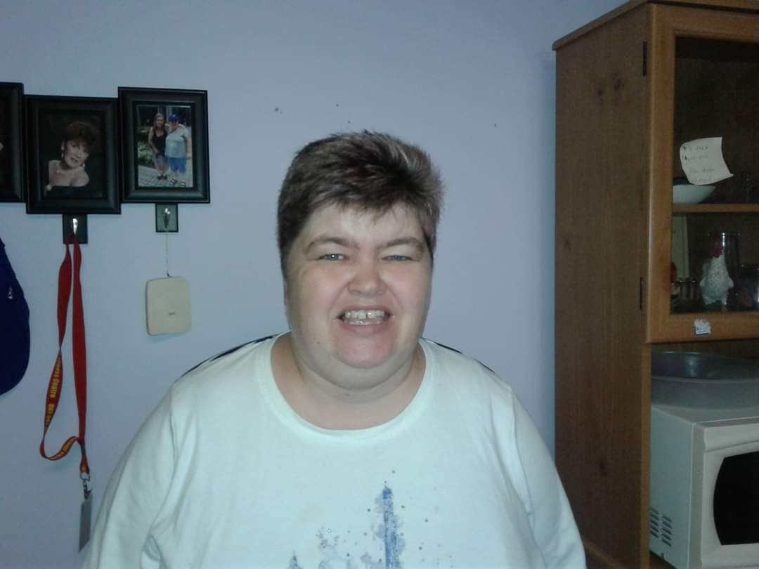 A woman in a white shirt is smiling in a room