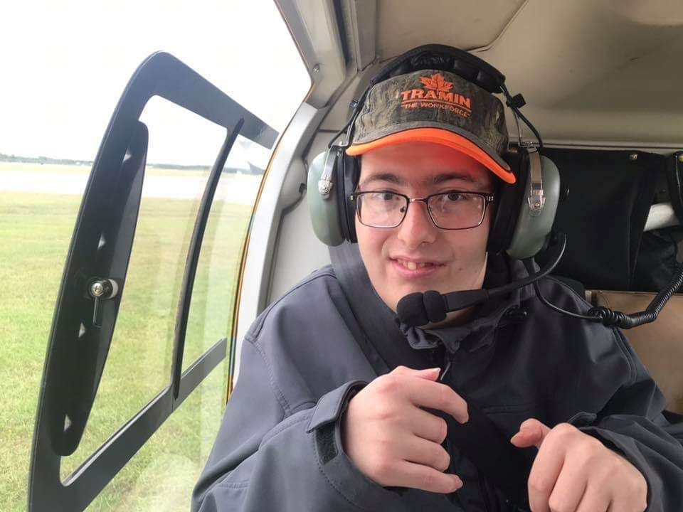 A man wearing a hat and headphones is sitting in a helicopter.