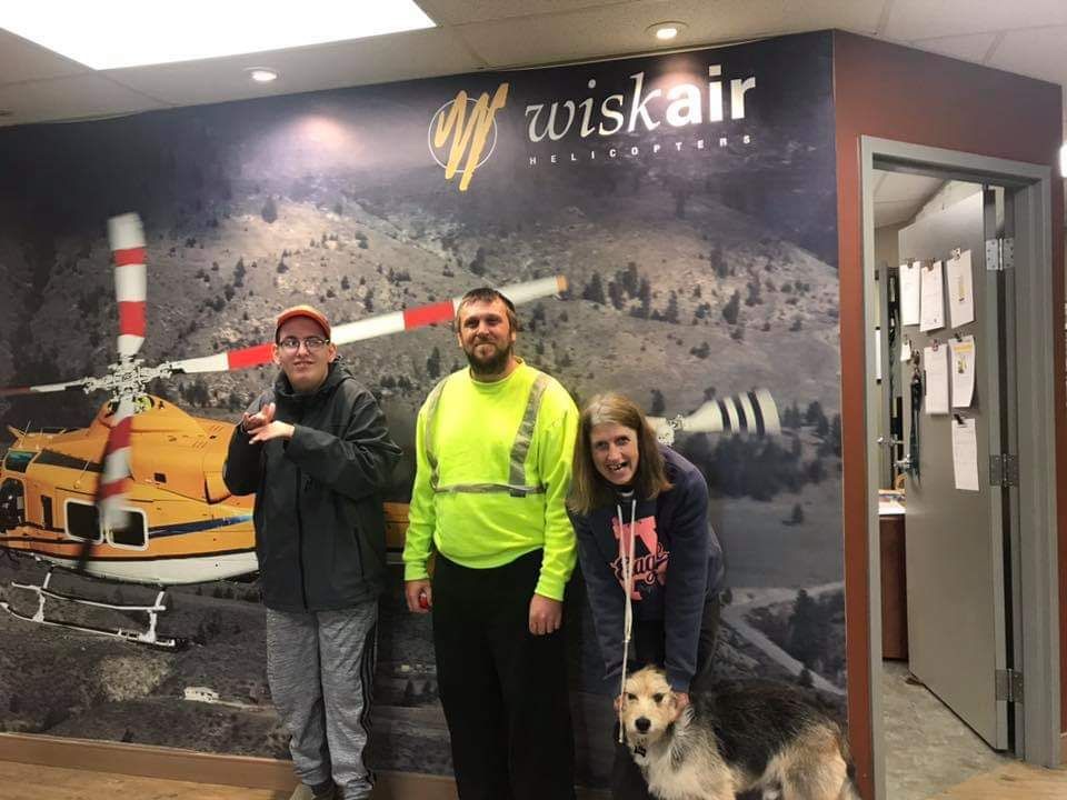 A group of people standing in front of a wall with a picture of a helicopter on it.