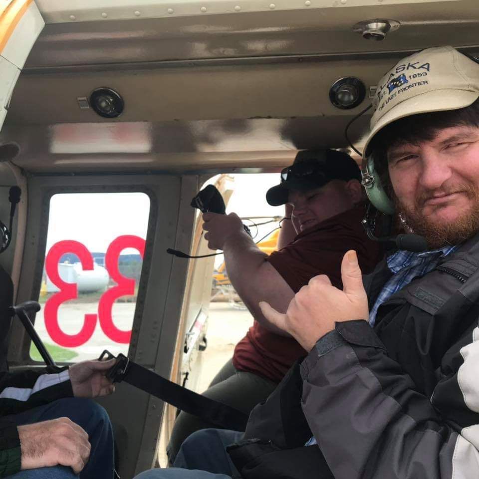 A man giving a thumbs up in a helicopter with the number 33 on the door