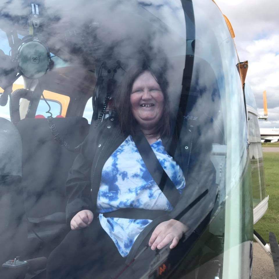 A woman in a blue tie dye shirt is sitting in a helicopter