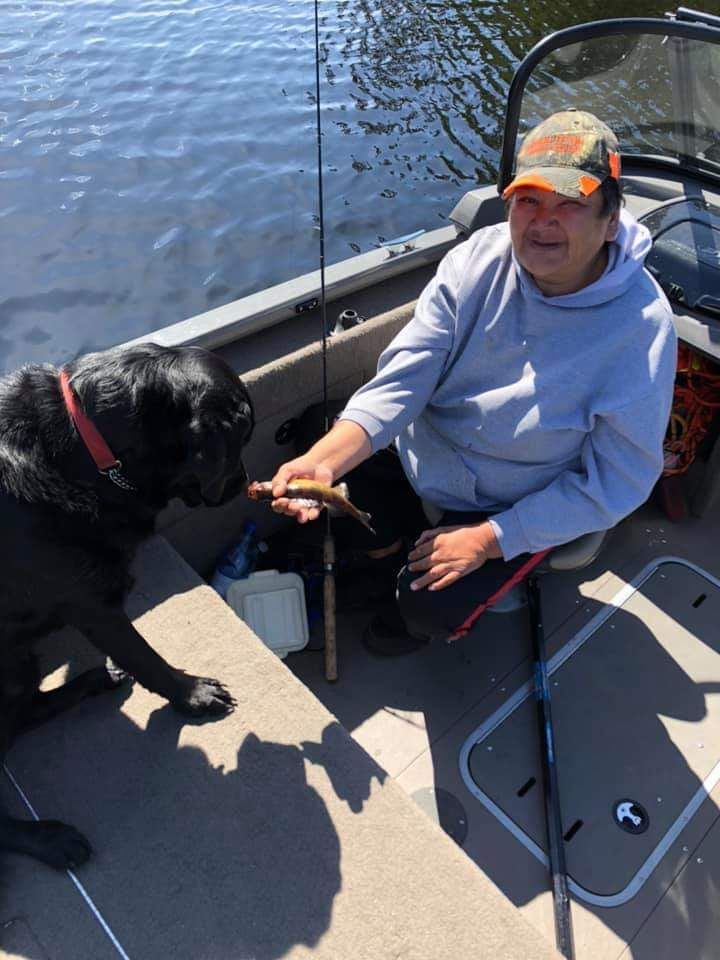 A man and a dog are fishing on a boat.