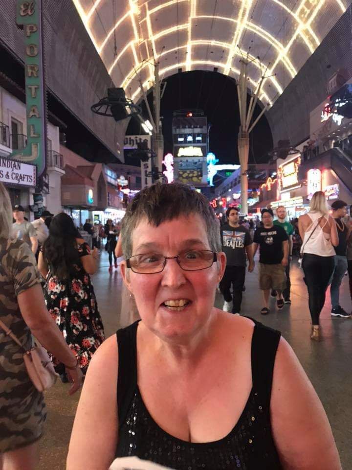 A woman wearing glasses is standing in a crowded street at night.