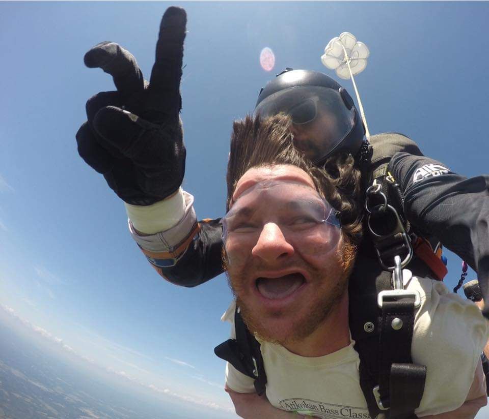 A man wearing a helmet and goggles is giving a peace sign