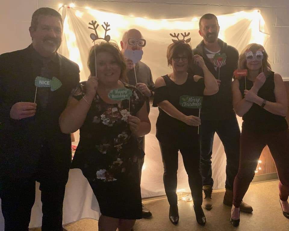 A group of people are posing for a picture in front of a white wall.