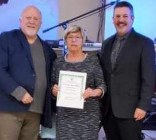 Two men and a woman are standing next to each other holding a certificate.