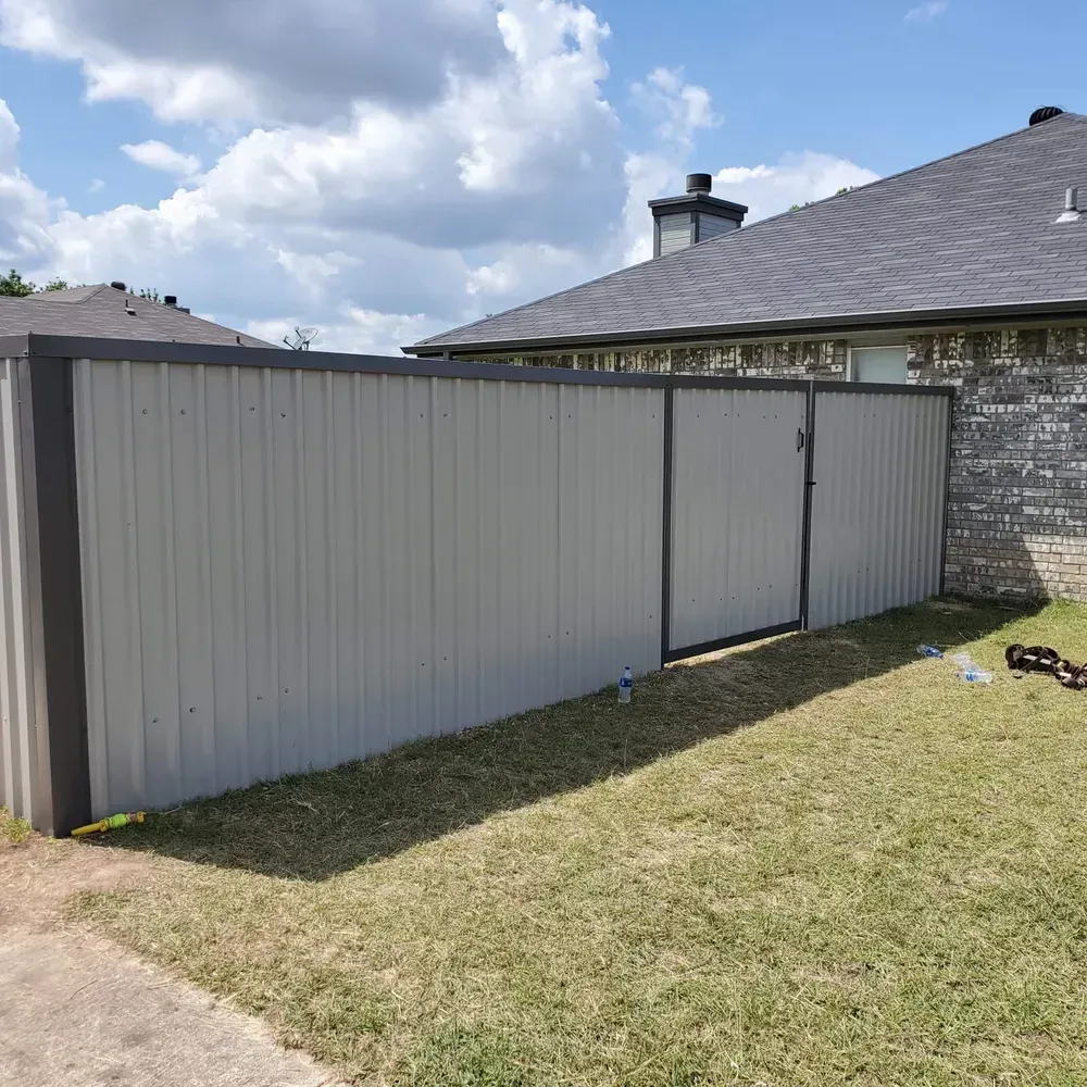 A metal fence is sitting in the grass in front of a house.