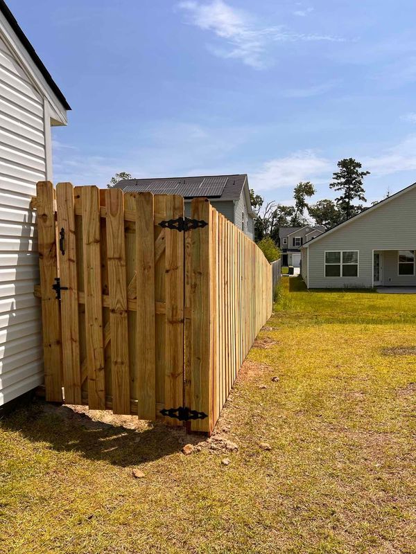 A wooden fence with a gate in the backyard of a house.