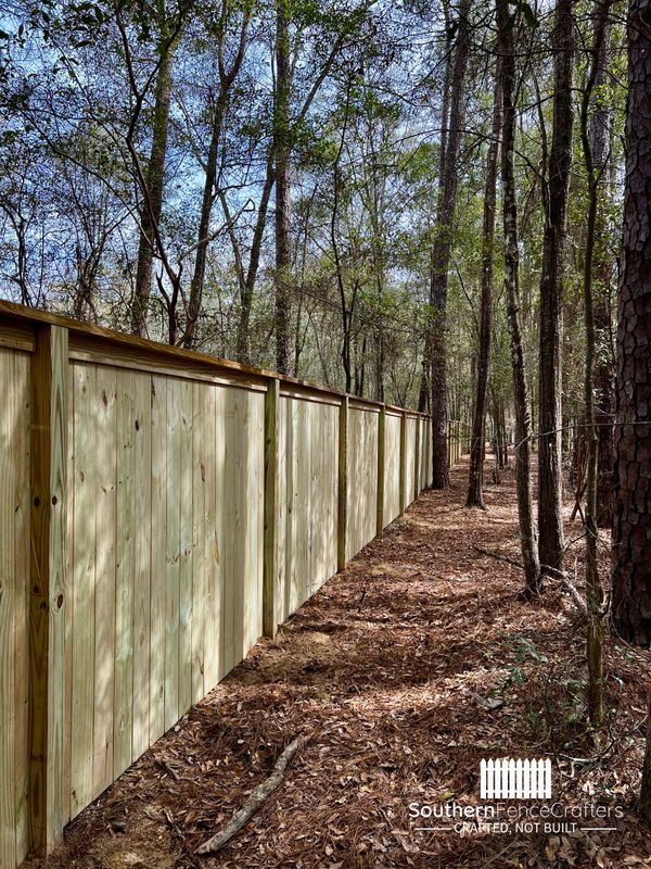 A wooden fence is surrounded by trees in the middle of a forest.