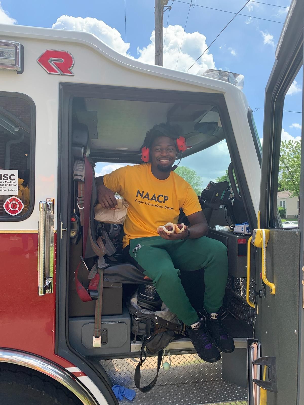 SEMO student sits in cab of fire truck at a street fair during canvassing day.