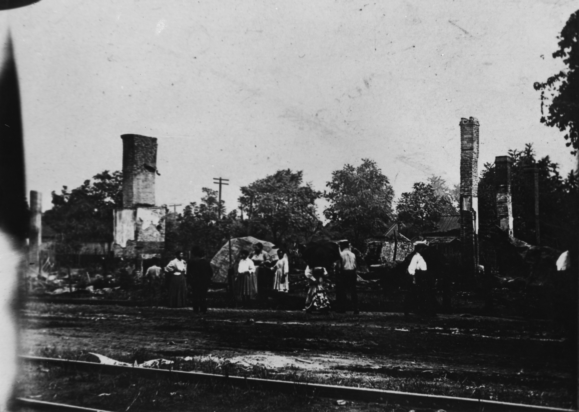 Black and white photo of African-American residents of Springfield, IL standing near some of the residences burned during the race riot of 1908.
