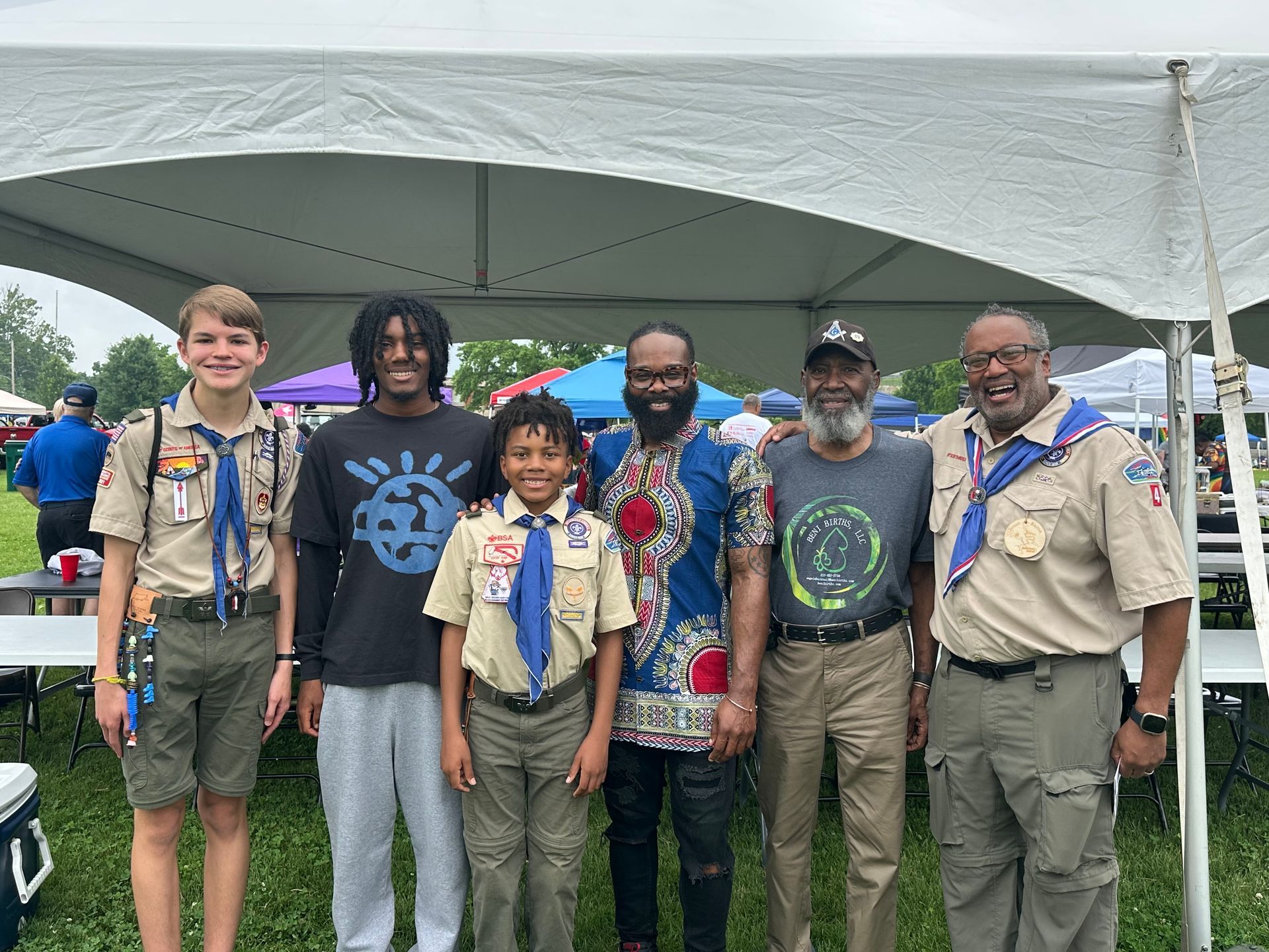 A group of boy scouts are posing for a picture under a tent.