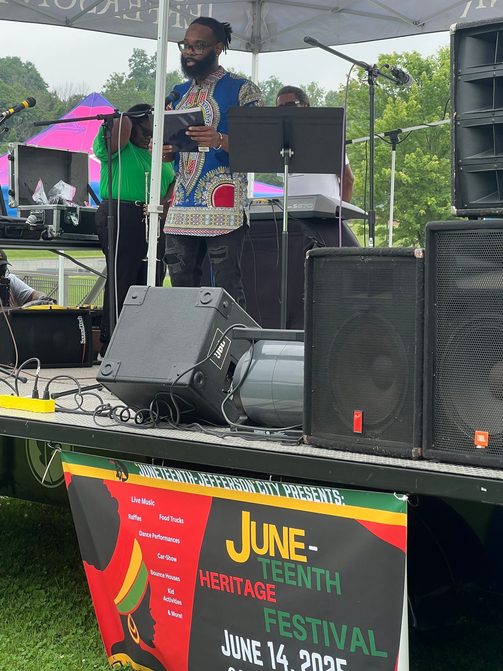 A man is standing on a stage with a sign that says juneteenth festival
