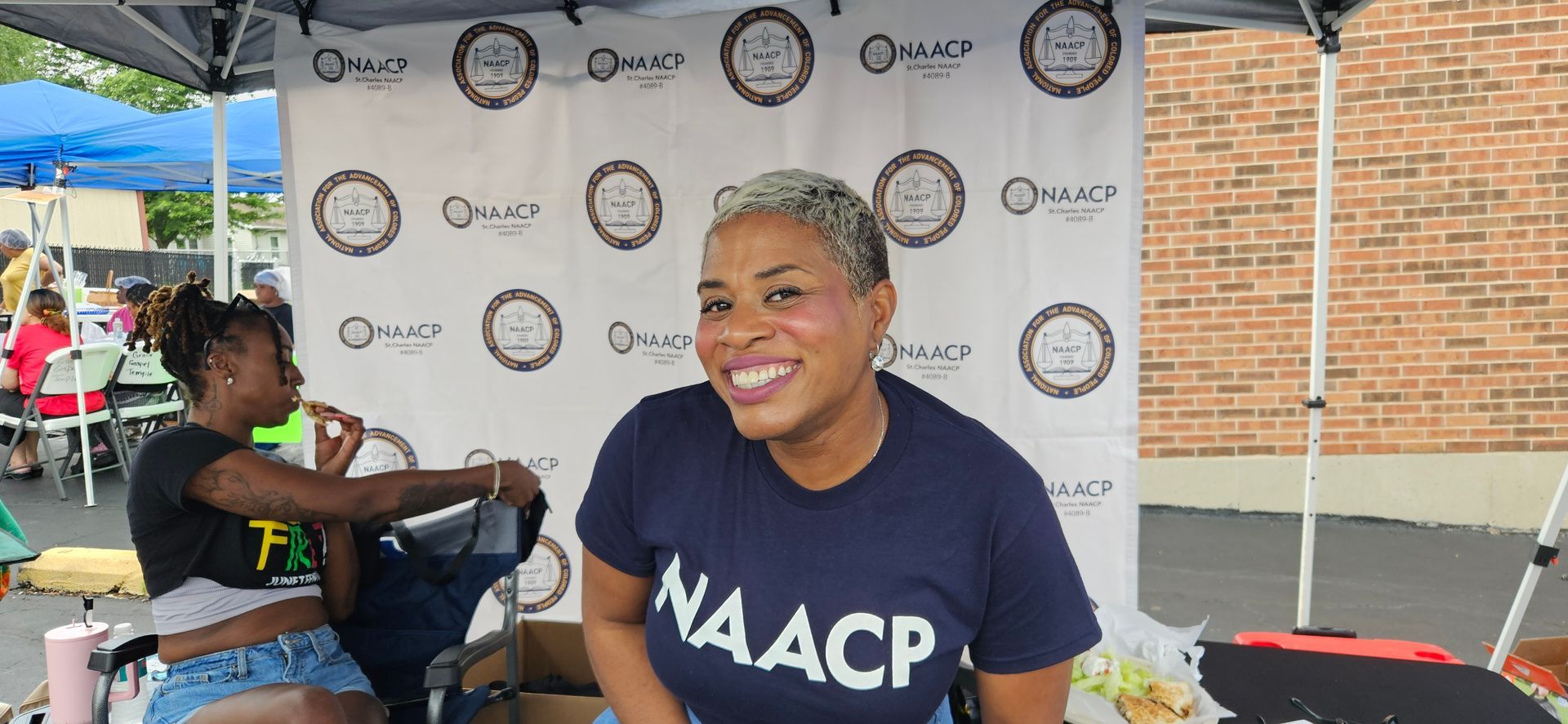 A woman wearing a naacp shirt is sitting at a table.