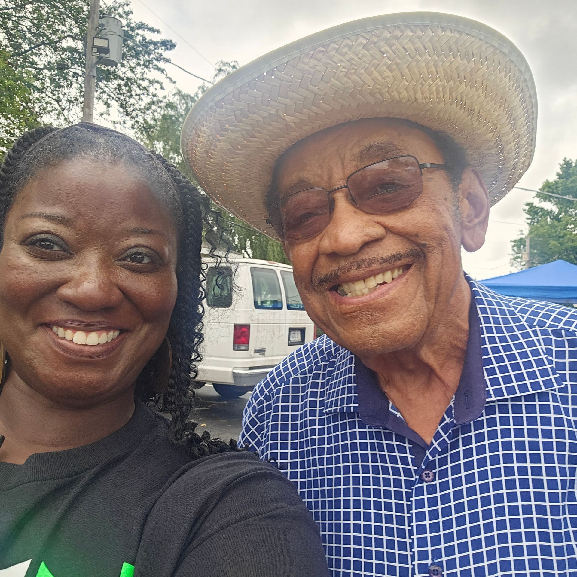 A man and a woman are posing for a picture and the man is wearing a straw hat