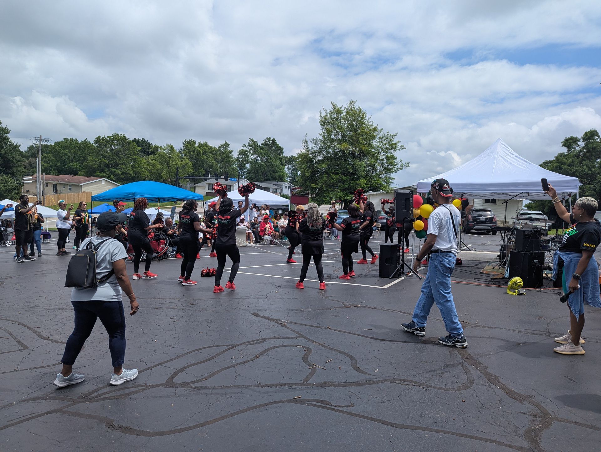 A group of people are dancing in a parking lot.