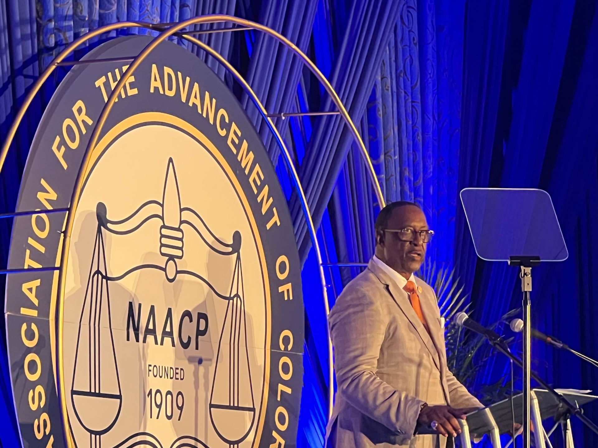 A man stands at a podium in front of a naacp logo