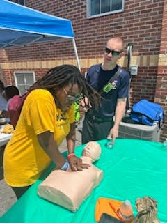 SEMO Student learns CPR on a dummy at the community event during a break from canvassing.