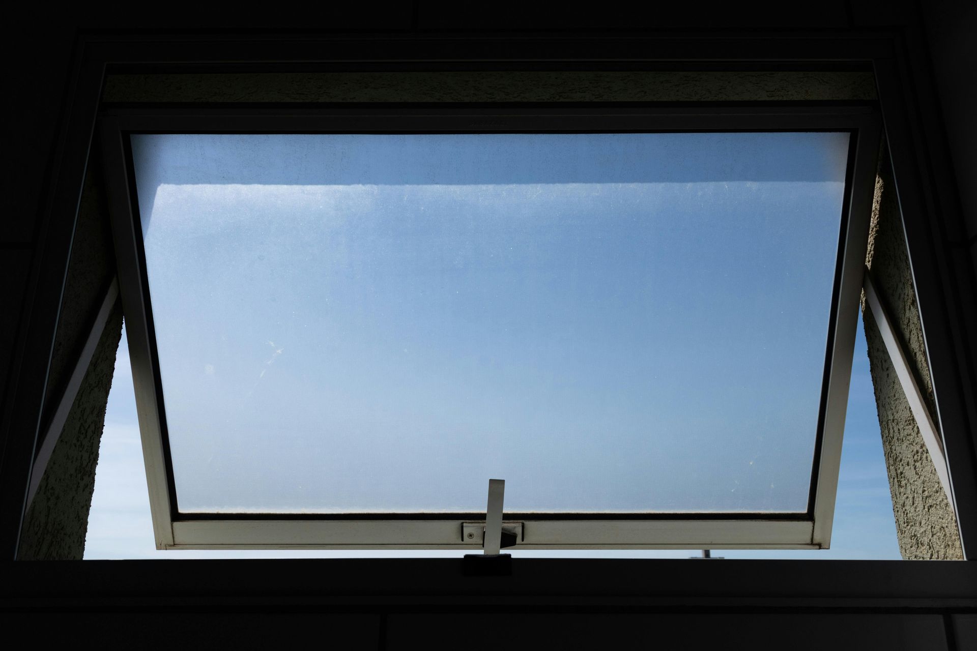 Open, white-framed window looking out at a blue sky.